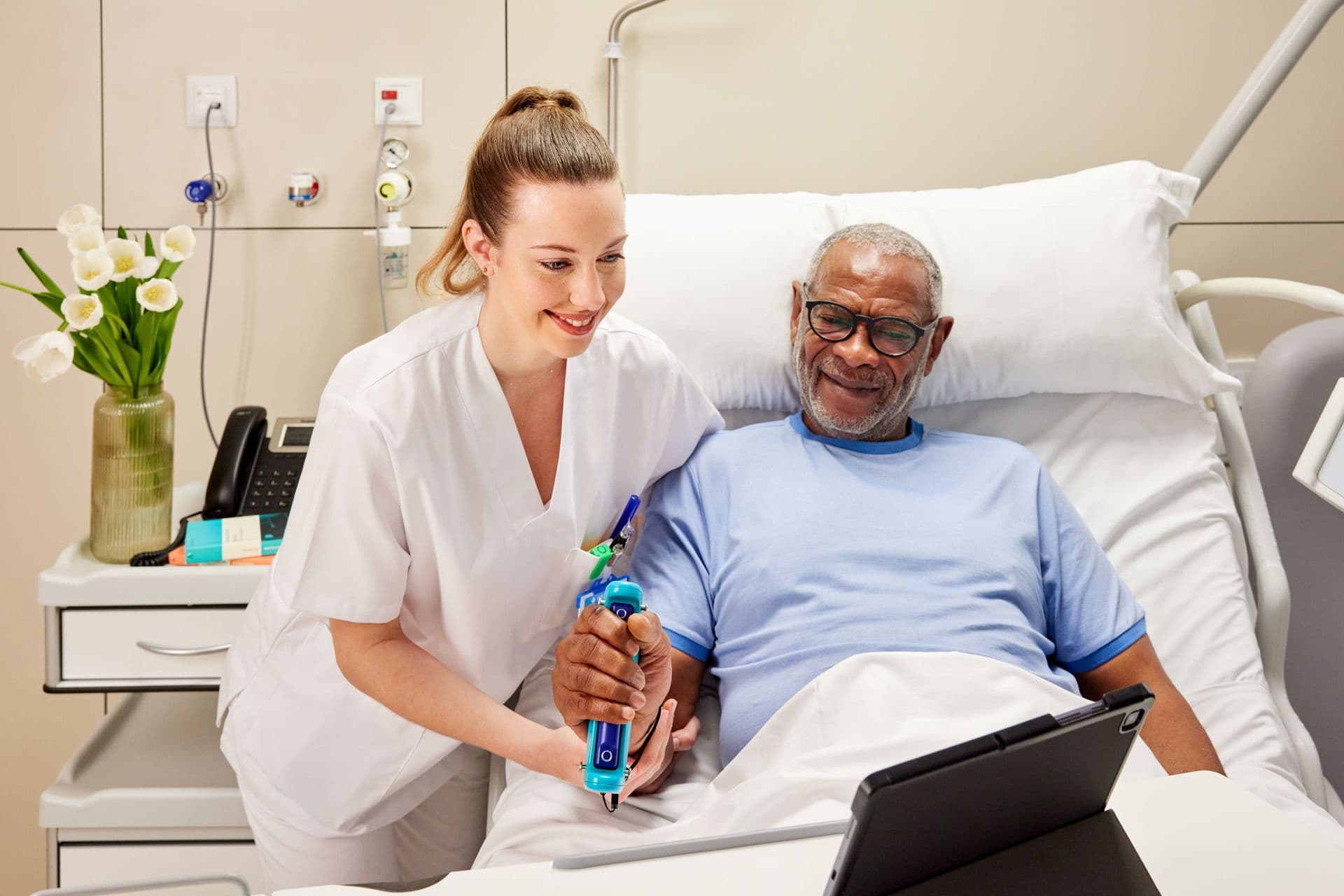 A clinician guiding an older woman through a GripAble grip-strength test with results on a tablet beside them